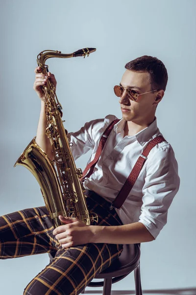 Guapo Joven Artista Gafas Sol Sosteniendo Saxofón Mirando Hacia Otro — Foto de stock gratis