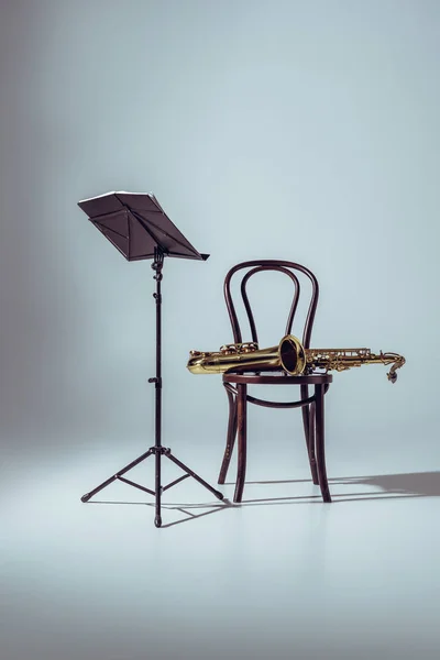 音乐代表音符和专业萨克斯在椅子上灰色 — 图库照片