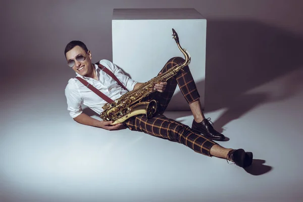 Smiling Young Musician Sunglasses Holding Saxophone While Lying Grey — Stock Photo, Image