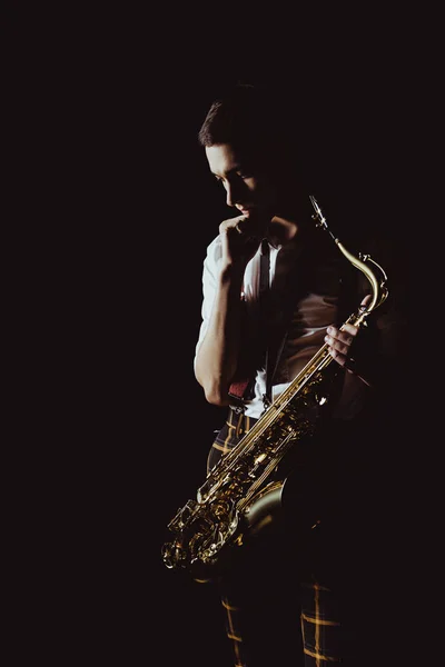 Jovem Músico Pensativo Segurando Saxofone Isolado Preto — Fotografia de Stock