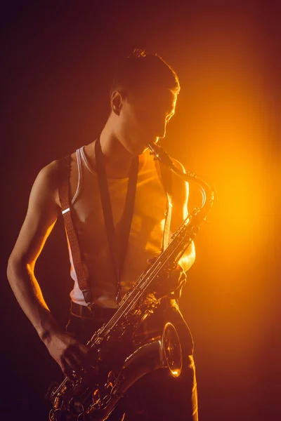 Hermoso Joven Jazzman Jugando Saxofón Contra Foco — Foto de stock gratis