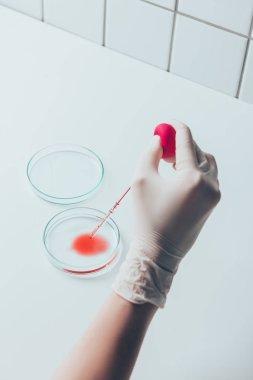 cropped shot of doctor pouring blood into petri dish clipart