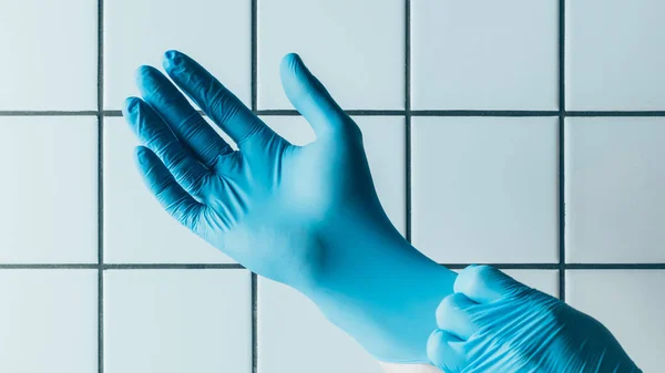 Tıbbi Işçi Mavi Kauçuk Eldiven Kiremitli Beyaz Duvar Önünde Koyarak — Stok fotoğraf