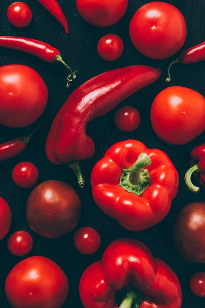 top view of red tomatoes, bell peppers and chili peppers on tabletop