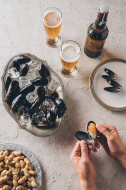 Erkek el, fıstık, midye ve bira masa üzerinde atış kırpılmış