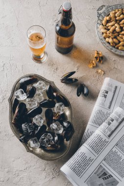 buz küpleri, bira, fıstık ve gazeteler ile midye üstten görünüm beton yüzeyi