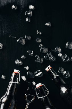 düz cam şişe bira şişe açacağı ile yatıyordu ve buz küpleri üzerinde karanlık masa üstü düzenlenmiş