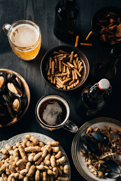 top view of table set with snacks and beer on dark wooden surface