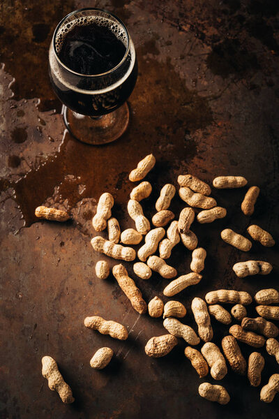 top view of mug of cold beer and peanuts on rust tabletop