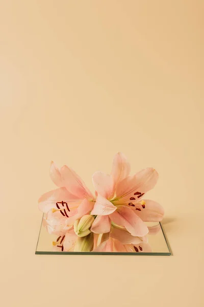ベージュ テーブル上のミラーにユリの花 — ストック写真