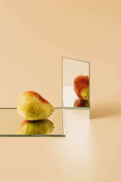 Yellow pear reflecting in two mirrors on beige table — Stock Image Yellow Pear Reflecting Two Mirrors Beige Table Stock Picture