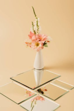 lily flowers in vase reflecting in mirrors on beige table  clipart