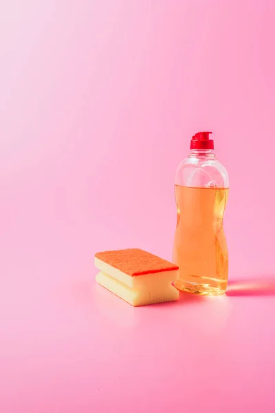 洗浄スポンジと食器洗いの液体 ピンクの背景のクローズ アップ表示 — ストック写真