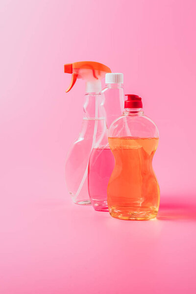 close up view of dishwashing liquid and cleaning fluids, pink background 