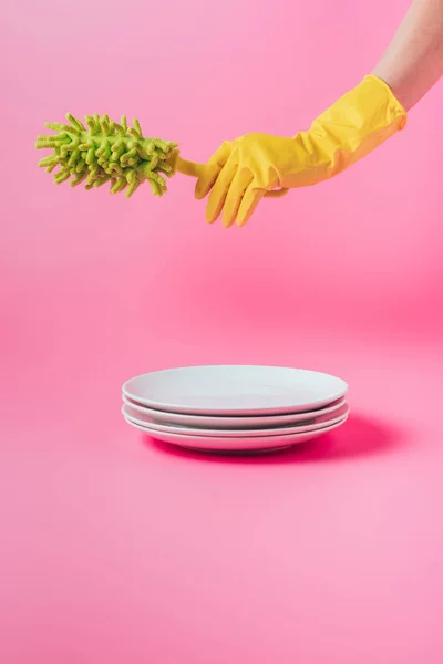 白いお皿にピンクの背景のスタックを皿の超極細繊維ブラシを保持しているゴム手袋の女性の画像をトリミング  — 無料ストックフォト
