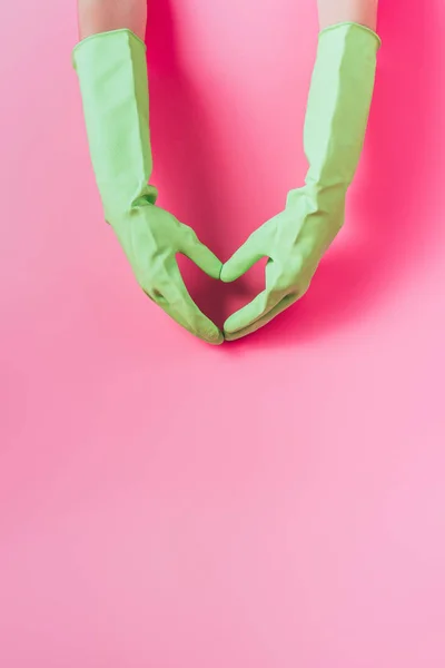 橡胶手套中女性清洁工的裁剪图像用手 粉红色背景制作心脏符号 — 图库照片