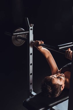 kadın vücut geliştirmeci halter, spor salonu, siyah arka plan ile egzersiz yaparak yüksek açılı görünüş 