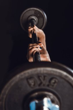 kadın atlet spor salonu, siyah arka plan, barbell ile egzersiz yaparak kısmi görünümünü