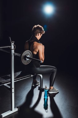 spor şişe kat, siyah arka plan üzerinde halter salonunda yakınındaki dinlenme boyun üzerinde havlu ile kadın vücut geliştirmeci