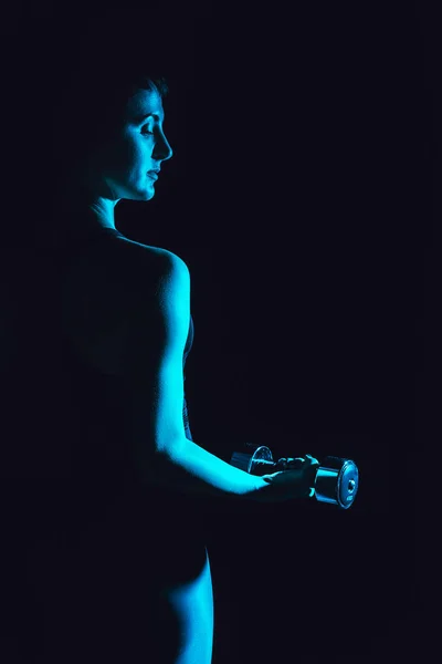 トーンのダンベル 黒の背景でワークアウト女性アスリートの画像  — 無料ストックフォト