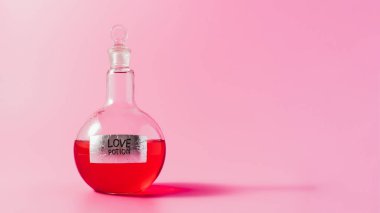 close-up shot of flask with red colored love potion on pink surface clipart