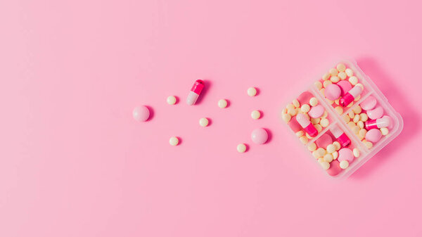 top view of plastic case with various pills on pink