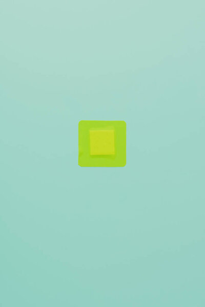 top view of green square adhesive bandage on blue