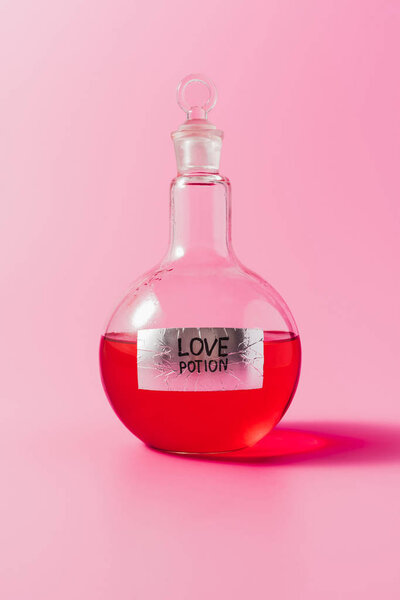 close-up shot of flask with red colored love potion on pink