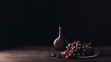 vintage plaka ve şişe şarap siyah ahşap masa üzerinde taze Olgun üzüm  