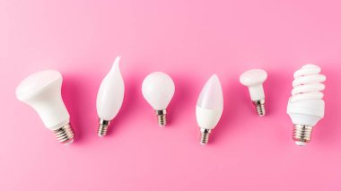 top view of various types of lamps on pink, energy concept clipart