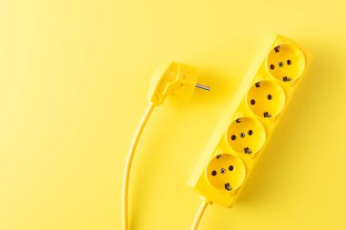 top view of yellow socket outlet and plug on yellow background