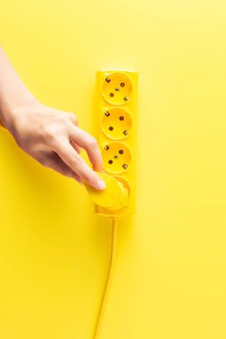 cropped shot of person inserting plug into socket outlet on yellow clipart