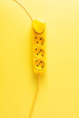 top view of bright yellow socket outlet with plug on yellow background clipart