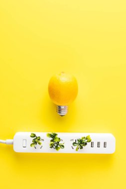 top view of light bulb made of lemon and socket outlet with green twigs on yellow background   clipart