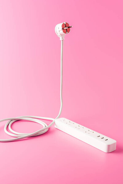close-up view of white socket outlet and plug isolated on pink