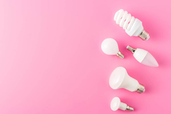 top view of various types of lamps on pink background 