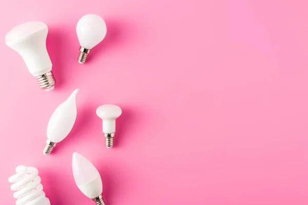 ピンクの背景にさまざまな種類の電球のトップ ビュー — ストック写真