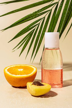 close up view of micellar water for skin care in bottle and orange half with water drops on beige background clipart