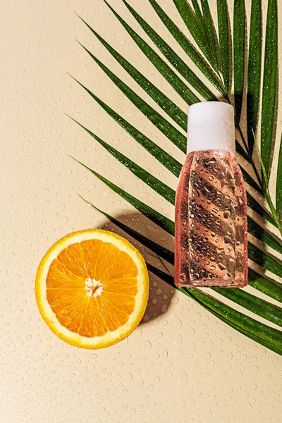 棕榈叶的顶部视图 瓶中的皮肤护理用胶束水和米色背景的橙半 — 图库照片