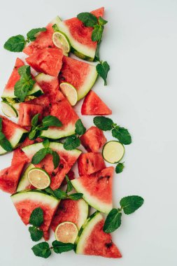 gri arka plan üzerinde kırmızı sulu karpuz ve limon dilimleri ile nane yaprakları, üstten görünüm