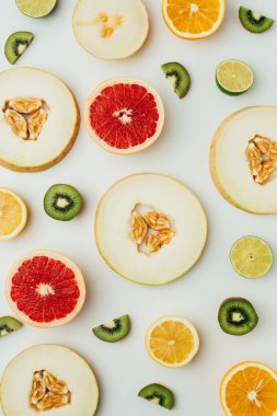top view of fresh melon, lime, grapefruit and kiwi slices, on grey background