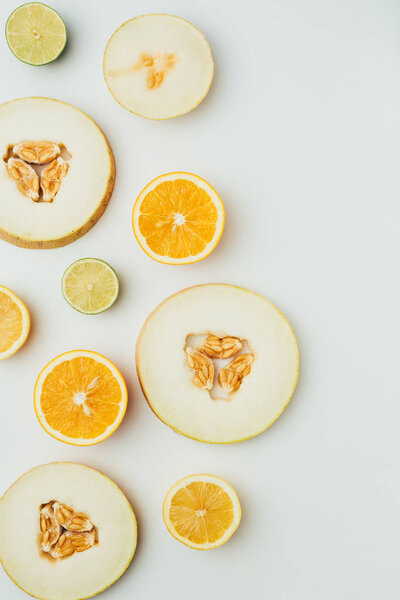 top view of melon, lime and orange slices, on grey background