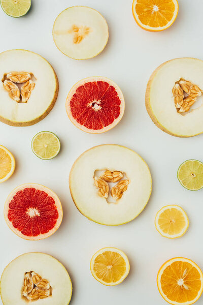 top view of fresh melon, lime and grapefruit and lemon slices, on grey background