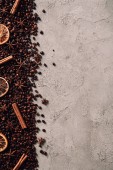 Draufsicht auf verschüttete Kaffeebohnen mit verschiedenen Gewürzen auf Betonoberfläche