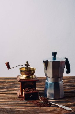 mocha pot and vintage coffee grinder on rustic wooden table clipart