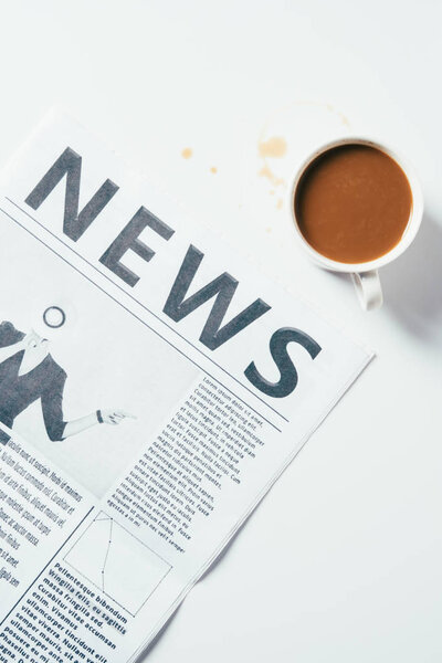 вид сверху на чашку кофе и газету на белой поверхности
