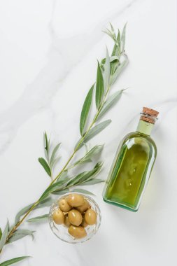 top view of bottle of olive oil and olives in bowl on marble table clipart