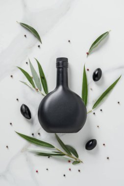siyah şişe zeytinyağı ve zeytin üstten görünüm mermer masada