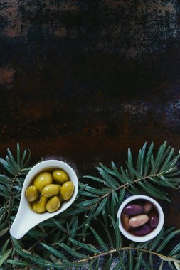elevated view of olives and twigs on shabby surface clipart