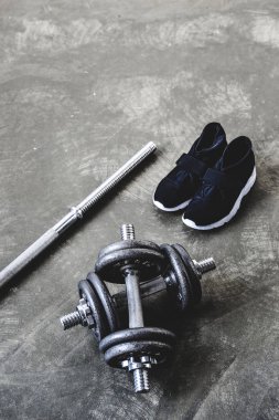 yakın çekim, spor ayakkabı ve beton yüzeyinde boş barı ayarlanabilir dambıl vurdu